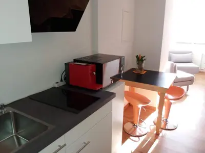 a kitchen with a red microwave and a counter with a table at Hotel Garni Frohsinn in Uttwil