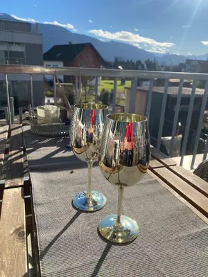 two wine glasses sitting on a table on a balcony at Mountain View luxury up to four persons in Diepoldsau