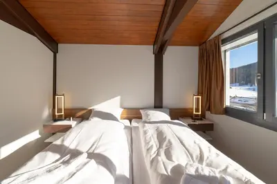 two beds in a room with two windows at Alpstern in Wildhaus