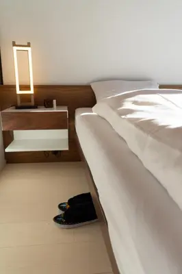 a bedroom with a white bed and a night stand at Alpstern in Wildhaus