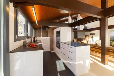 a kitchen with white cabinets and black counter tops at Alpstern in Wildhaus