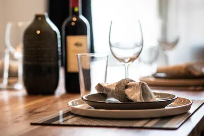 a plate with a napkin on a table with wine bottles at Schöne Wohnung im Herzen von Herisau bis 6 Gäste in Herisau