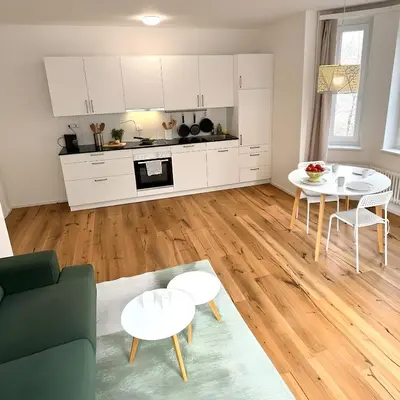a kitchen and living room with white cabinets and tables at Gemütliche und geräumige 2,5 Zimmer Wohnung mit kostenlosem Parkplatz in St. Gallen
