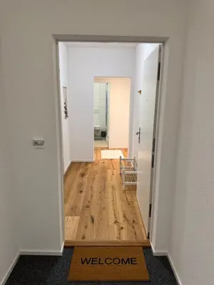 a hallway with a door leading to a room with a welcome mat at Gemütliche und geräumige 2,5 Zimmer Wohnung mit kostenlosem Parkplatz in St. Gallen