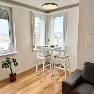 a living room with a table and chairs and windows at Modernes, renoviertes Apartment nähe dem Zentrum kostenloses Parken in St. Gallen