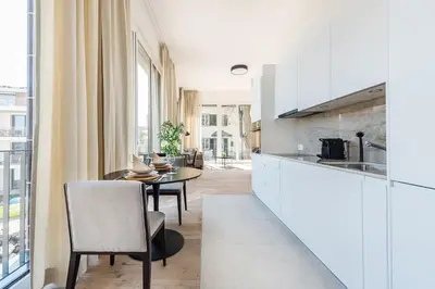a kitchen with white cabinets and a table with chairs at DESIGN-STUDIO 4 !Gratis Parken, Free Parking! in Kreuzlingen