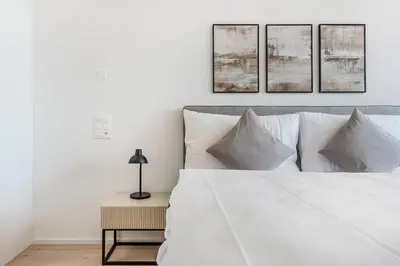 a bedroom with a white bed with four pictures on the wall at DESIGN-STUDIO 4 !Gratis Parken, Free Parking! in Kreuzlingen