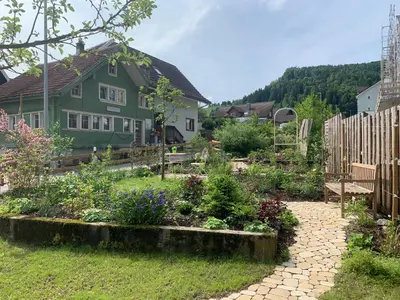 a garden in front of a green house at Gemütliches Chalet-Zimmer in Guesthouse Rosalie in Brunnadern