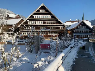 a large wooden building with snow on the ground at Gemütliches Chalet-Zimmer in Guesthouse Rosalie in Brunnadern