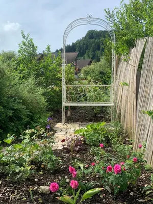 a garden with a bench in a garden with flowers at Private Apartment in Guesthouse Rosalie in Brunnadern