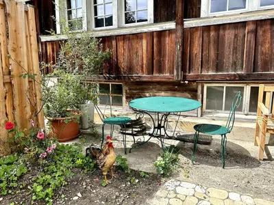 a table and chairs and a chicken in a backyard at Private Apartment in Guesthouse Rosalie in Brunnadern