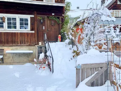 a yard covered in snow in front of a house at Private Apartment in Guesthouse Rosalie in Brunnadern