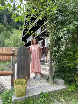 a woman standing on the steps of a house at Private Apartment in Guesthouse Rosalie in Brunnadern