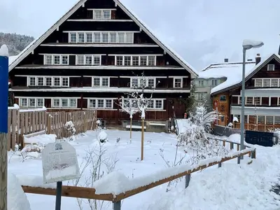a large wooden house with snow on the ground at Historical Guesthouse Rosalie in Brunnadern
