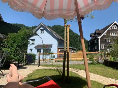 a person sitting in a chair under an umbrella at Historical Guesthouse Rosalie in Brunnadern