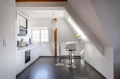 a kitchen with white cabinets and a stool in a room at Private Apartment in Degersheim