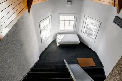 a stairs with a bed in a room with two windows at Private Apartment in Degersheim