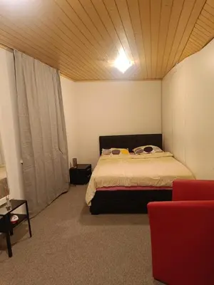 a bedroom with a bed and a red couch at Como apartamento en el centro de st Gallen in St. Gallen