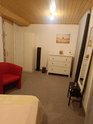 a bedroom with a bed and a dresser and a red couch at Como apartamento en el centro de st Gallen in St. Gallen