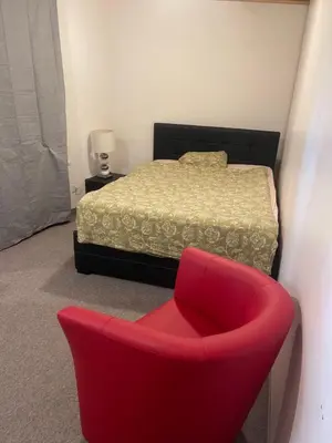 a bedroom with a bed and a red chair at Como apartamento en el centro de st Gallen in St. Gallen