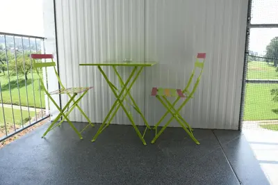 two green chairs and a table on a balcony at Towerhotel in Waldkirch