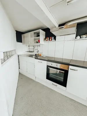 a kitchen with white cabinets and a sink at Central city apartment with terrace in St. Gallen