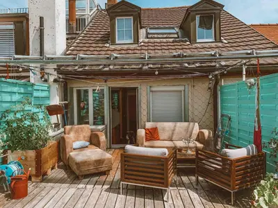 a patio with two chairs and a table and a house at Central city apartment with terrace in St. Gallen