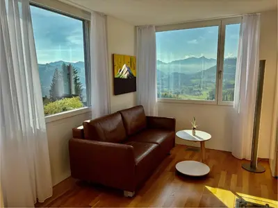 a living room with a couch and two large windows at Appenzellerland, 2 Zimmer Ferienwohnung mit Aussicht in Haslen