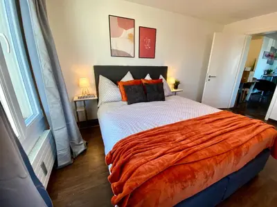 a bedroom with a large bed with an orange blanket at Modern Lakeview Apartment in Romanshorn