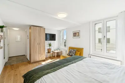 a white bedroom with a large bed and a chair at Klara 1014 - Olma, Spital, Uni St- Gallen in St. Gallen