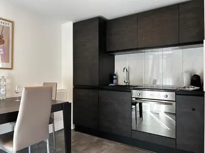 a kitchen with black cabinets and a table and a sink at Klara 1014 - Olma, Spital, Uni St- Gallen in St. Gallen