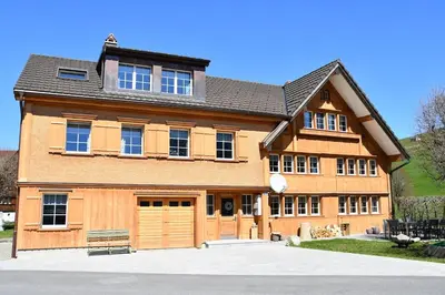 a large wooden house with a garage at Haus Ritzlisjokes in Weissbad