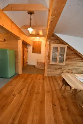 an empty living room with a wooden floor and a table at Haus Ritzlisjokes in Weissbad