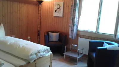 a bedroom with a bed and a chair and a lamp at Wenk Elisabeth in Wildhaus