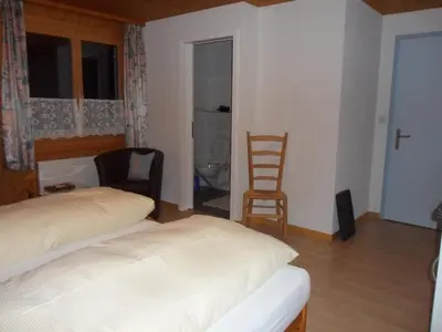 a bedroom with a bed and two chairs and a window at Wenk Elisabeth in Wildhaus