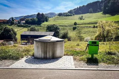 a trash can and a green bin on the side of a field at Zum Wöschhüsli mit Sauna in Rheineck