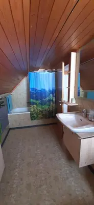 a bathroom with a tub and a shower curtain at Ferienwohnung Toggilodge in Unterwasser