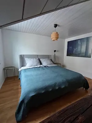a bedroom with a large bed with a blue blanket at Bijou petit -mit Terrasse in Rorschach