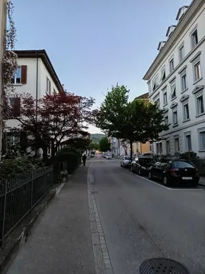a person riding a bike down a street with buildings at Bijou petit -mit Terrasse in Rorschach