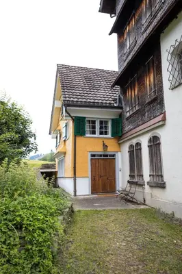 a yellow and white house with a brown door at Wohnhaus Münzmühle in Appenzell in Appenzell