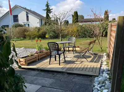 a patio with a table and chairs in a yard at Zimmer am See in Goldach
