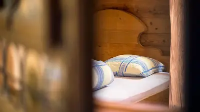 a bed with a wooden headboard and two pillows at Hotel Badhof in Altstätten