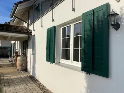 a window with green shutters on the side of a building at Traumwohnung in 3 Minuten zum Bodensee in Dozwil