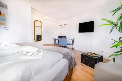 a white bedroom with a bed and a table at VISIMO Apartments Teufenerstrasse St Gallen - Urban, Direct, Close to nature in St. Gallen