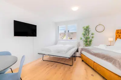 a white room with two beds and a tv at VISIMO Apartments Teufenerstrasse St Gallen - Urban, Direct, Close to nature in St. Gallen