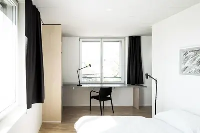 a bedroom with a chair and a bed and a window at Gästehaus Meiersegg - HotelFlawil in Flawil