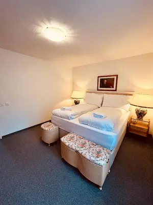 a bedroom with a bed with two ottomans at Gemütliches und geräumiges Apartment für Familien und Gruppen mit Seeblick in Heiden