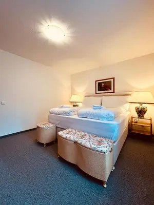 a hotel room with two beds and two ottomans at Gemütliches und geräumiges Apartment für Familien und Gruppen mit Seeblick in Heiden