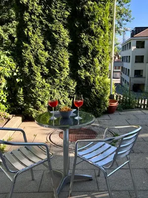two glasses of wine sitting on a table with two chairs at Charmantes Studio in Teufen in Teufen
