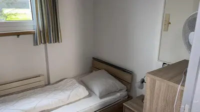 a small bed in a small room with a window at Herberge Seeperle Bistro Rorschach in Rorschach